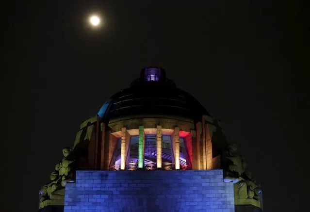 The moon is seen over the illuminated dome of the Monument to the Revolution in Mexico City November 23, 2015. Landmark buildings were illuminated after Mexico City's Mayor Miguel Angel Mancera declared on Monday the Mexican capital as a "Rainbow City", friendly to gay, lesbian, bisexual, transsexual, transvestite, transgender and intersexual communities (LGBTTTI), according to local media. (Photo by Daniel Becerril/Reuters)