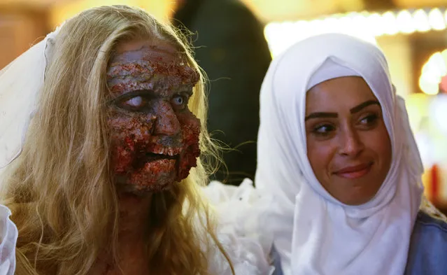 A Muslim woman poses for a picture with a zombie bride during a so-called “Zombie walk” through the western German city of Essen on Halloween Day, October 31, 2016. (Photo by Wolfgang Rattay/Reuters)