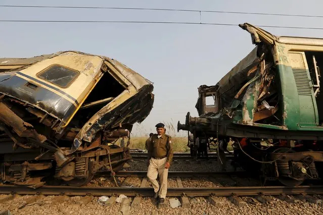 A policeman walks next to the damaged coaches of a passenger train after a collision near Palwal in the northern state of Haryana, India, December 8, 2015. (Photo by Anindito Mukherjee/Reuters)