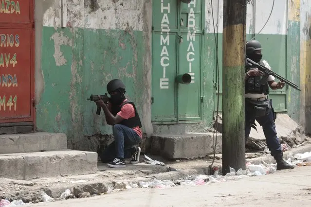 Police officers take cover during an anti-gang operation in the Portail neighborhood of Port-au-Prince, Haiti, Tuesday, April 25, 2023, a day after a mob in the Haitian capital pulled 13 suspected gang members from police custody at a traffic stop and beat and burned them to death with gasoline-soaked tires. (Photo by Joseph Odelyn/AP Photo)