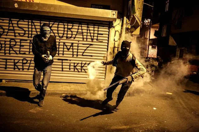 An armed Kurdish militant throws back a tear gas canister towards Turkish riot police during clashes in the Okmeydani district of Istanbul following a demonstration against recent curfews imposed on Kurdish towns on December 15, 2015. The Turkish government has been waging a relentless offensive aimed at crippling the rebel Kurdistan Workers' Party (PKK), which has staged a string of attacks against security forces in Turkey since a two-year-old ceasefire fell apart in late July. (Photo by Cagdas Erdogan/AFP Photo)