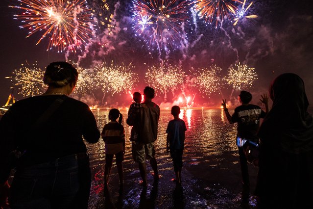 Local residents look at fireworks as they celebrate the New Year at Ancol Beach in Jakarta on January 1, 2025. (Photo by Yasuyoshi Chiba/AFP Photo)