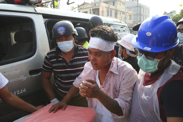 An injured protester is escorted as police tried to disperse a demonstration against the military coup in Mandalay, Myanmar, Friday, February 26, 2021. (Photo by AP Photo/Stringer)