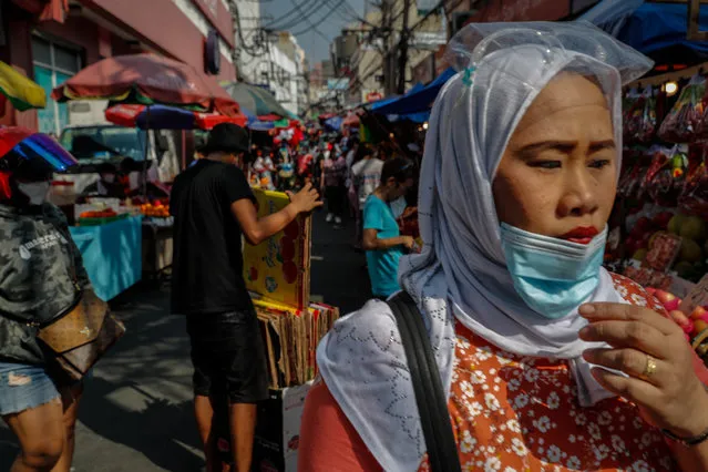 A woman pulls down her mask at a public market in Manila, Philippines, 24 December 2020. Despite going on nine months of COVID 19 quarantine measures and reminders from authorities to observe social distancing outdoors, bargain markets have become crowded before Christmas Day as shoppers make last minute buying sprees for gifts for their loved ones. (Photo by Mark R. Cristino/EPA/EFE)