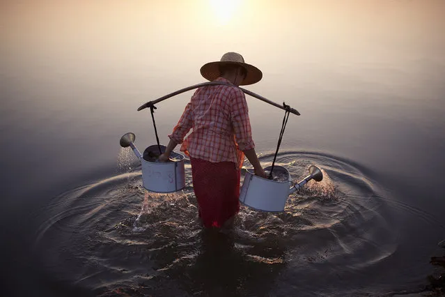 Merit Winner: “Lady in Water”. A lady collects water in the river by a village in Bagan, Myanmar, 2013.  Location: Bagan, Myanmar. (Photo and caption by Marcelo Salvador/National Geographic Traveler Photo Contest)