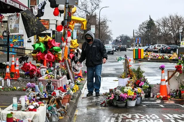 A man removes dead flowers from the makeshift memorial of George Floyd before the third day of jury selection begins in the trial of former Minneapolis Police officer Derek Chauvin who is accused of killing Floyd, in Minneapolis, Minnesota on March 10, 2021. The first jurors were selected on March 9, 2021 in the high-profile trial of the white police officer accused of killing George Floyd, an African-American man whose death laid bare racial wounds in the United States and sparked "Black Lives Matter" protests across the globe. Former Minneapolis Police Department officer Derek Chauvin is facing charges of second-degree murder and manslaughter in connection with Floyd's May 25 death, which was captured by bystanders on smartphone video. (Photo by Chandan Khanna/AFP Photo)