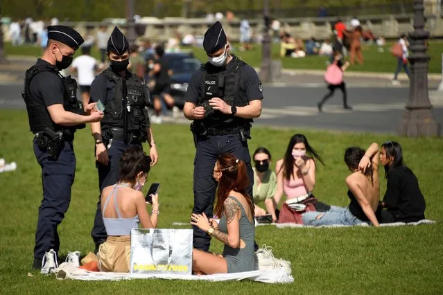 Police officers control people enjoying a sunny spring day on the grassin front of the Hotel des Invalides in Paris, amidst the coronavirus pandemic, on March 31, 2021. (Photo by Bertrand Guay/AFP Photo)