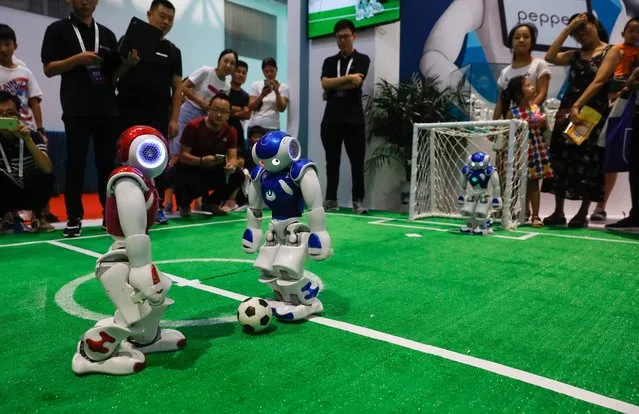 Visitors watch robots playing football during the 2018 World Robot conference in Beijing, China, 15 August 2018. The conference will be held from 15 to 19 August and will include a conference on robotics, an exhibition and a robot competition with the participation of robotics enterprises to showcase their robot products. (Photo by Roman Pilipey/EPA/EFE/Rex Features/Shutterstock)