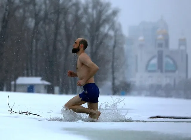 A man runs out of an ice-hole in the Dniper River in Kiev, January 5 2016. The temperature in the Ukrainian capital fell to -12 degrees Celsius (10 degrees Fahrenheit) on Tuesday. (Photo by Sergei Chuzavkov/AP Photo)