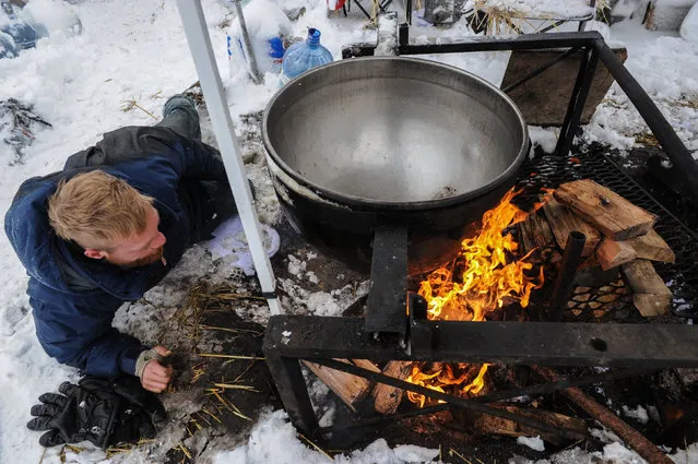 A man makes a fire under a large cooking pot in the Oceti Sakowin camp during a protest against plans to pass the Dakota Access pipeline near the Standing Rock Indian Reservation, near Cannon Ball, North Dakota, U.S. November 29, 2016. (Photo by Stephanie Keith/Reuters)