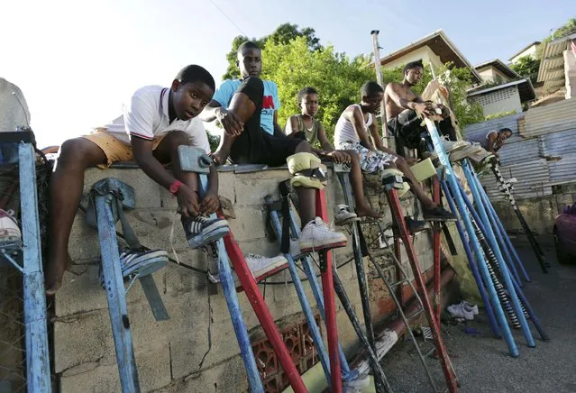 Members of the Keylemanjahro School of Art and Culture sit on a brick wall as they strap on their stilts, prior to a practise sessions in the base yard at Harding Place, Cocorite, just West of the capital of Port-of-Spain, Trinidad, on February 8, 2015. (Photo by Andrea De Silva/Reuters)