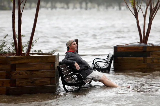 A man sits on a park bench in a flooded park as the Cape Fear River rises above its usual height in Wilmington, North Carolina, U.S., September 14, 2018. (Photo by Jonathan Drake/Reuters)