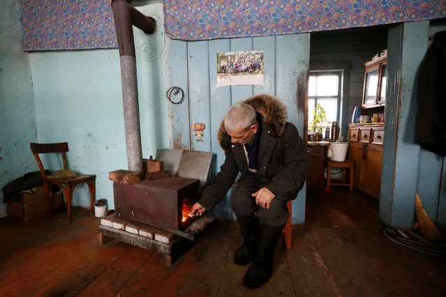 Mikhail Baburin, 66, stokes a furnace at his house in the remote Siberian village of Mikhailovka, Krasnoyarsk region, Russia, December 5, 2016. (Photo by Ilya Naymushin/Reuters)