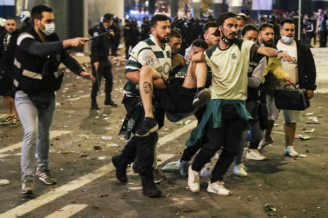Sporting of Lisbon fans carry a man after clashing with police outside at Alvalade Stadium during the the First League Soccer match of Spo​rting against Boavista in Lisbon, Portugal, 11 May 2021. (Photo by Miguel A. Lopes/EPA/EFE)