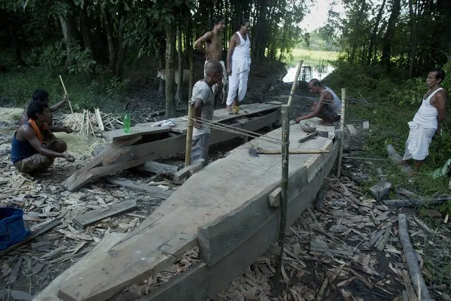 In this August 6, 2018 photo, monks, in white, instruct carpenters making boats at a Vaishnavite Hindu monastery in Majuli, in the northeastern Indian state of Assam. Majuli is said to be one of the largest river islands in the world, surrounded by the fast-moving waters of the massive, though braided, Brahmaputra river. The island, known as the cultural capital of Assam with its Hindu religious Vaishnavite monasteries, floods every year with water ripping its banks, inundating homes, claiming lives and lands. (Photo by Anupam Nath/AP Photo)