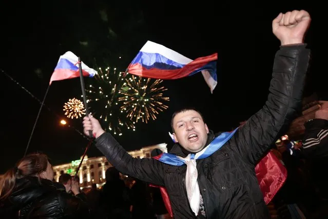 In this In this Sunday, March 16, 2014 file photo people with Russian flags celebrate a referendum on seceding from Ukraine and seeking annexation by Russia, in Lenin Square in Simferopol, Crimea. (Photo by Ivan Sekretarev/AP Photo)