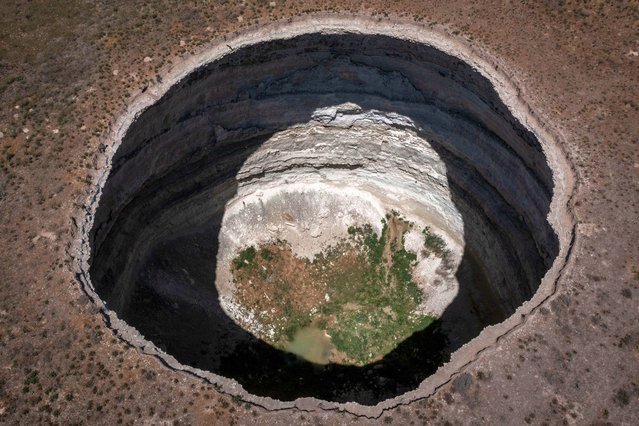 In an aerial view, a massive sinkhole is seen on the outskirts of a village on June 03, 2021, in Karapinar, Turkey. In Turkey’s Konya province, the heart of the country's agriculture sector, extreme drought conditions over the past two years are taking a heavy toll on farmers and the land. Konya province produces more than 2.5 million tons of grain every year, but the lack of rainfall in the past six months has dramatically reduced grain harvests and is raising concerns over future crops. According to Turkey's Statistical Institute (TURKSTAT) grain production in Turkey is predicted to drop 5.5% from last year. For farmers the lack of rain gives them little option but to tap into the groundwater supplies to sustain their crops, forcing some farmers to turn to installing illegal ground wells. However, the reliance on groundwater has seen underground water levels drop by more than two meters in the past five years, contributing to an increase in massive sinkholes across the province worrying farmers as they spread closer to residential areas. Konya has the second largest number of sinkholes in the world behind Florida. More than 600 sinkholes dot the landscape and drought conditions are making the situation worse. According to Geology Professor Fetullah Arik, who heads the Sinkhole Application And Research Centre at the Konya Technical University, the number of sinkholes has doubled since last year’s count. (Photo by Chris McGrath/Getty Images)