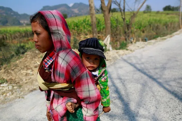 A woman displaced by recent violence carries her baby as she walks down a road, in Laukkai February 17, 2015. (Photo by Soe Zeya Tun/Reuters)