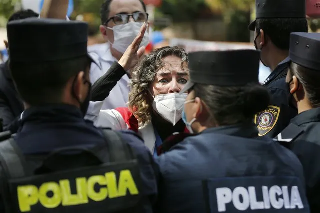 Dr. Rosa Morinigo is blocked by police as she and others from the doctors' union try to reach the presidential residence to protest for better working conditions and resources to fight COVID-19, in Asuncion, Paraguay, Friday, May 14, 2021. (Photo by Jorge Saenz/AP Photo)
