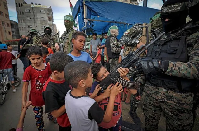 Palestinian boys hold a gun belonging to a member of the Ezz-Al Din Al-Qassam Brigades in Gaza City on June 14, 2021. (Photo by Mahmud Hams/AFP Photo)