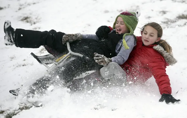 Stella Knipp, 10 of Evansville and Kylee Lowery, 10, of Newburgh wipe out in the snow while sledding in Newburgh Wednesday after a winter storm brought about 3 inches of snow Wednesday morning forcing schools to close in the area Wednesday January 20, 2016, in Newburgh, Ind. (Photo by Jason Clark /Evansville Courier & Press via AP Photo)