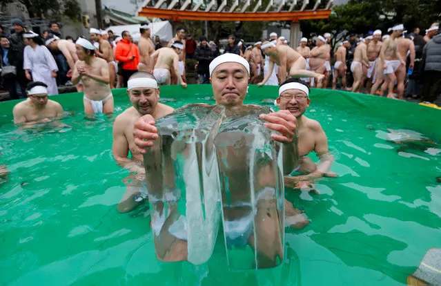 Men wearing loin cloths hold on to ice as they bathe in ice-cold water outside the Teppozu Inari shrine in Tokyo, Japan, January 8, 2017. According to organizers, about 100 participants took part in the Shinto ceremony to purify their souls and wish for good health in the new year. (Photo by Toru Hanai/Reuters)