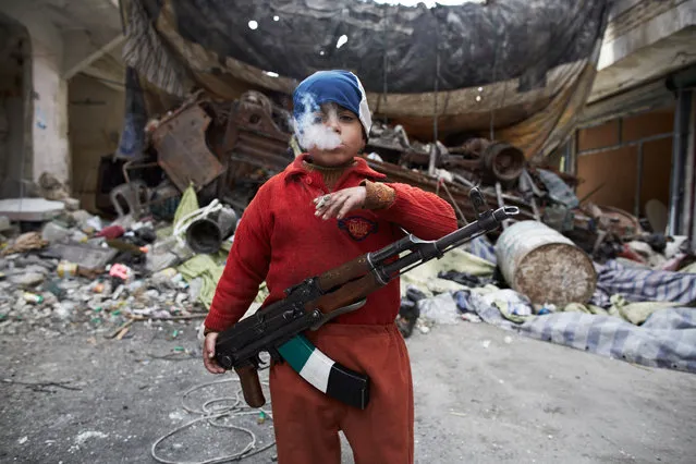 Ahmed, the 7 year old son of a FSA fighter, stands in front of a barricade, were he assits his FSA comrades in the neighborhood of Salahadeen, one of Aleppo's front lines. Aleppo, Syria, on March 27, 2013. (Photo by Sebastiano Tomada/Sipa Press USA)