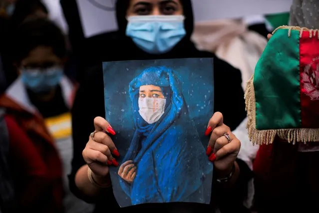 A woman holds a photograph during a protest to raise awareness regarding the situation in Afghanistan outside EU headquarters in Brussels, Wednesday, August 18, 2021. The European Union has no immediate plans to recognize the Taliban after their sweeping victory in Afghanistan but will talk with the militants to ensure that European nationals and Afghans who have worked with the EU can leave safely, the bloc's top diplomat said Tuesday. (Photo by Francisco Seco/AP Photo)