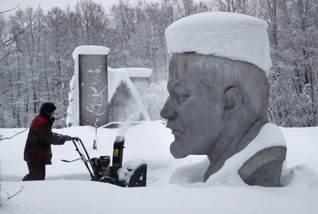 A worker clears snow next to the snow covered statue of Soviet Union founder Vladimir Lenin at the Lenin Hut Museum in a forest near Razliv Lake, outside St. Petersburg, Russia, Monday, February 4, 2019. Another cyclone caused a week of snowfall in St. Petersburg. (Photo by Dmitri Lovetsky/AP Photo)