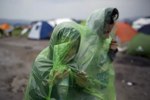 Two girls wearing raincoats walk in front of tents, as refugees wait to be allowed to cross the the Greek-Macedonian border near the northern Greek village of Idomeni , Wednesday, February 24, 2016. The Greek interior ministry said about 12,000 people have been stranded in Greece since neighbor Macedonia began turning Afghan immigrants away at the border and slowing the number of crossings for others heading to central and northern Europe. (Photo by Petros Giannakouris/AP Photo)