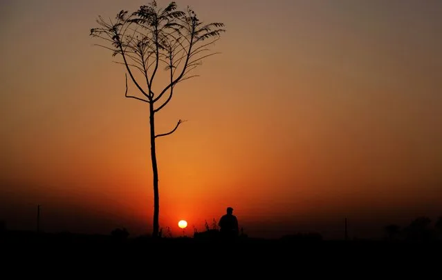 A boy is silhouetted against the sunset as he waits for his friends on a highway on the outskirts of Islamabad, Pakistan, Wednesday, February 17, 2016. (Photo by Anjum Naveed/AP Photo)