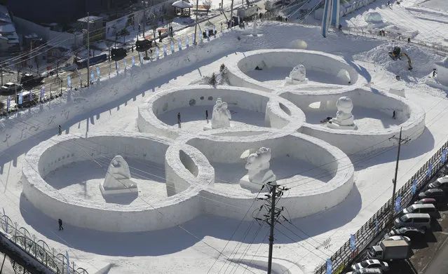 Visitors tour near the snow sculpture in the shape of the Olympic rings displaying at the Daegwanryung Snow festival in Pyeongchang, South Korea, Friday, February 3, 2017. South Korea's Pyeongchang is the host city of the 2018 Olympic and Paralympic Winter Games which will start from February 2018. (Photo by Lee Jin-man/AP Photo)