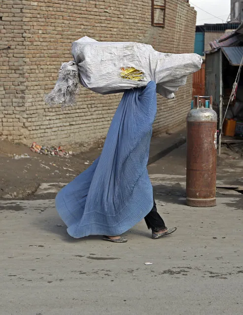 An Afghan woman carries a sack of firewood on her head in Kabul, Afghanistan, Wednesday, January 27, 2016. (Photo by Rahmat Gul/AP Photo)