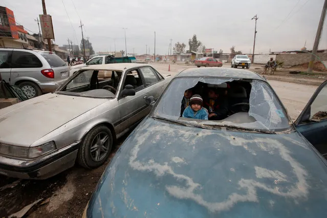 Children are seen through a window of the broken car at an industrial neighborhood of Mosul, Iraq, January 31, 2017. (Photo by Azad Lashkari/Reuters)