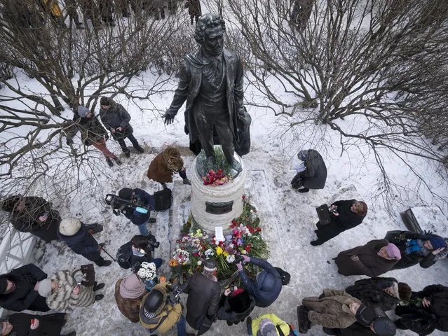 People put flowers on the monument of Alexander Pushkin, marking 180th anniversary of his death, in the yard of a museum, an apartment on Moika River Embankment, the last place where the outstanding Russian poet lived in St.Petersburg, Russia, Friday, February 10, 2017. Pushkin was fatally wounded in a duel and died in this building in 1837. (Photo by Dmitri Lovetsky/AP Photo)