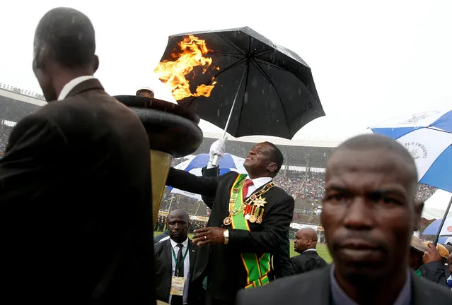 Zimbabwe's President Emmerson Mnangagwa shelters under an umbrella as he lights the country's Independence flame during anniversary celebrations in Harare, Zimbabwe, April 18, 2019. (Photo by Philimon Bulawayo/Reuters)