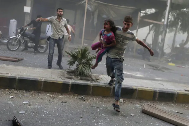 A man carries an injured girl after what activists said were five air strikes by forces loyal to Syria's President Bashar al-Assad in Douma, eastern al-Ghouta, near Damascus September 11, 2014. (Photo by Bassam Khabieh/Reuters)