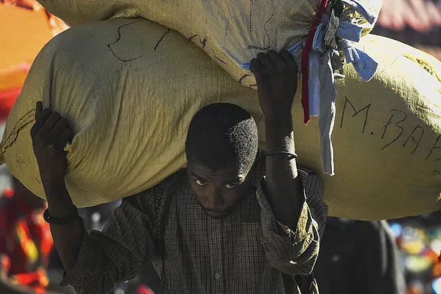 A vendor carries his bags of clothing for several blocks to his market stall, instead of using a tap tap bus due to a fuel shortage, in Port-au-Prince, Haiti, Thursday, November 11, 2021. (Photo by Matias Delacroix/AP Photo)