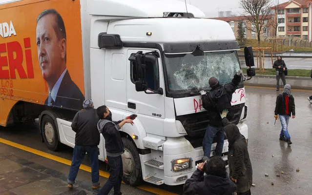 A demonstrator breaks the window of a truck of Turkey's ruling Justice and Development Party (AKP) featuring a picture of Turkish Prime Minister Recep Tayyip Erdogan during clashes with riot police at a demonstration against the opening of a controversial new road development that will include a part of the Middle East Technical University campus in Ankara on February 25, 2014. (Photo by Adem Altan/AFP Photo)
