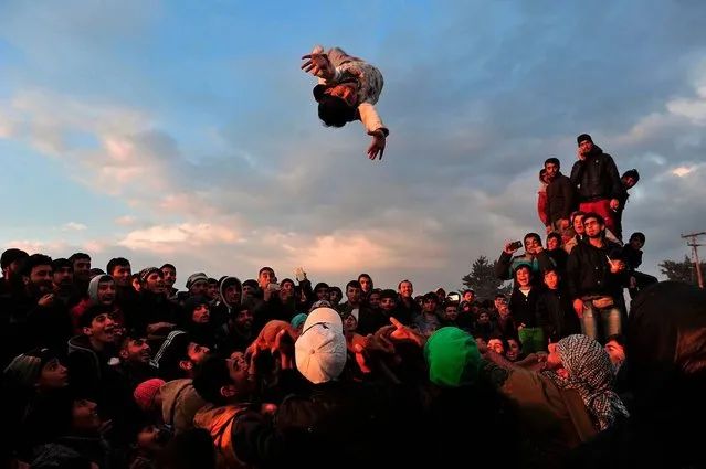 People make a child jump in the aire thanks to a blanket at the makeshift camp of the Greek-Macedonian border, near the Greek village of Idomeni on March 27, 2016, where thousands of refugees and migrants are stranded by the Balkan border blockade. Dozens of hopeful refugees, some carrying babies, rushed to Greece's overwhelmed Idomeni camp on the sealed border with Macedonia on March 27, 2016 following rumours that the frontier would be forced open. The influx came as Greek authorities were trying to evacuate an estimated 11,500 people already stranded at the squalid camp after Balkan states slammed shut their borders, cutting off the migrant route to the European Union. (Photo by Sakis Mitrolidis/AFP Photo)