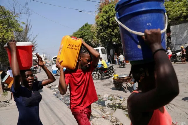 People carry water collected in buckets and containers along a street after Haiti's Prime Minister Ariel Henry pledged to step down following months of escalating gang violence, in Port-au-Prince, Haiti on March 12, 2024. (Photo by Ralph Tedy Erol/Reuters)