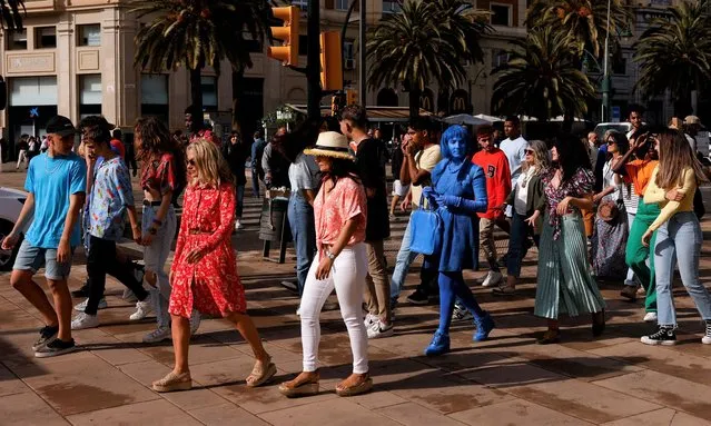 People walk as they prepare to be extras for an Dutch advertising spot of fruit-flavoured beverages in central Malaga, Spain, April 28, 2022. (Photo by Jon Nazca/Reuters)