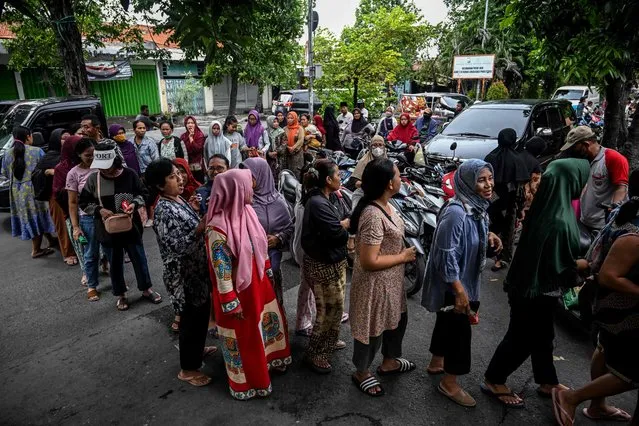 People queue in line to buy basic daily necessities at a cheap market event held by the government in Surabaya to maintain stable food supplies and prices on March 12, 2024. (Photo by Juni Kriswanto/AFP Photo)