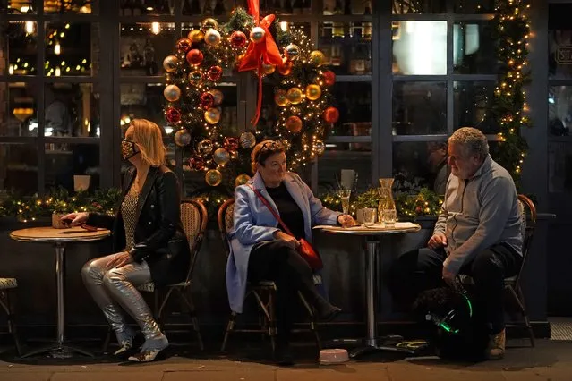 People sit on outdoor tables outside a restaurant on Old Compton Street in Soho, London on Thursday, December 16, 2021, where new restrictions have come into force to slow the spread of the Omicron variant of coronavirus. (Photo by Kirsty O'Connor/PA Images via Getty Images)