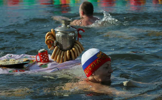 A woman swims next to a samovar floating in a pond during celebration of Maslenitsa, or Pancake Week, a pagan holiday marking the end of winter, in Podolsk, Russia, February 26, 2017. (Photo by Maxim Shemetov/Reuters)