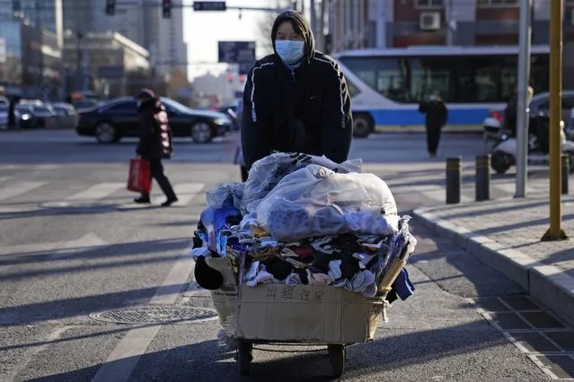 A street vendor wearing a mask to curb the spread of the coronavirus pushes a cart along the street in Beijing, China, Wednesday, December 29, 2021. (Photo by Ng Han Guan/AP Photo)