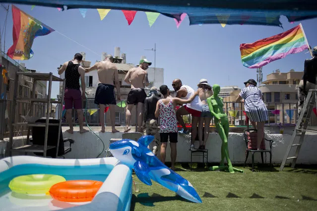 People watch from their roof top at the annual Gay Pride Parade in Tel Aviv, Tel Aviv, Israel, Friday, June 12, 2015. Thousands of bare-chested muscular men, drag queens in heavy makeup and high heels, women in colorful balloon costumes and others partied at Tel Aviv's annual gay pride parade on Friday, the largest event of its kind in the region. (AP Photo/Ariel Schalit)