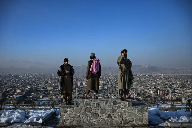 Members of the Taliban stand over a plinth overlooking the Kabul city  at the Wazir Akbar Khan hill in Kabul on January 10, 2022. (Photo by Mohd Rasfan/AFP Photo)