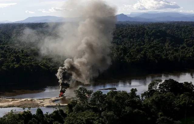 An illegal gold dredge is seen burning down at the banks of Uraricoera River during Brazil’s environmental agency operation against illegal gold mining on indigenous land, in the heart of the Amazon rainforest, in Roraima state, Brazil April 15, 2016. (Photo by Bruno Kelly/Reuters)