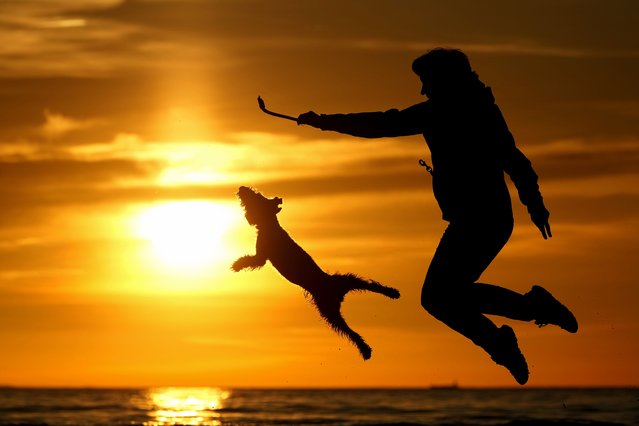 A woman plays with her dog at a beach on the Gulf of Finland as the sun sets, in St. Petersburg, Russia, Wednesday, May 15, 2024. (Photo by Dmitri Lovetsky/AP Photo)